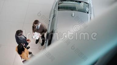 从高角度看年轻家庭<strong>买</strong>车与销售员握手拥抱